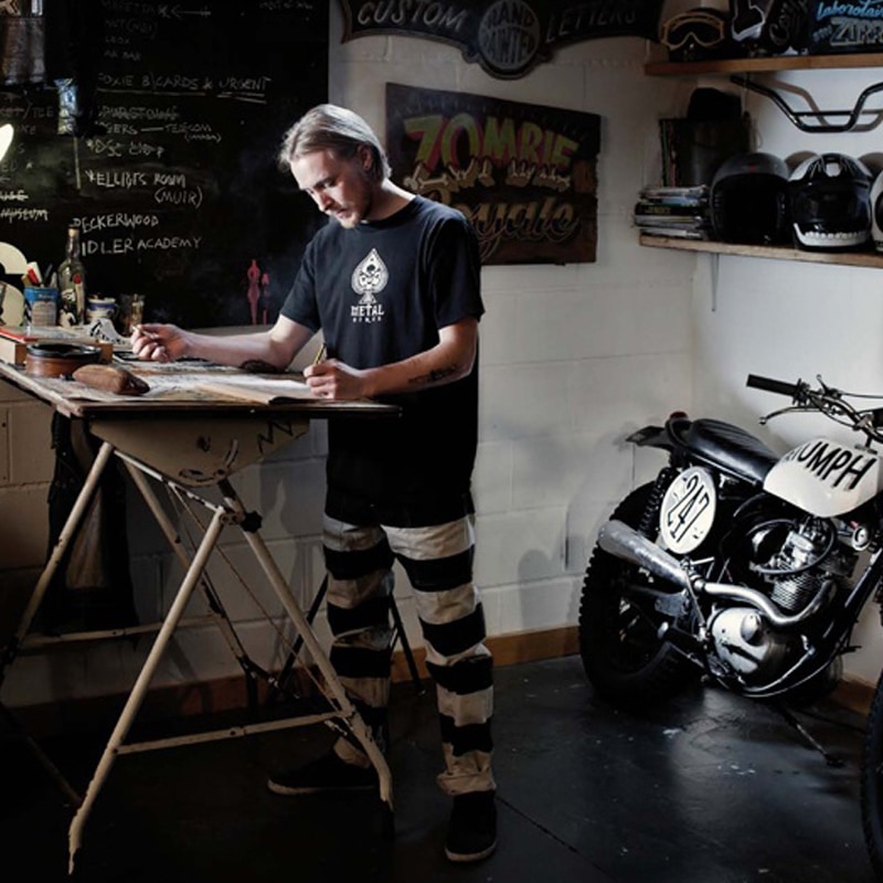 Man standing at drawing board with motorbike in background