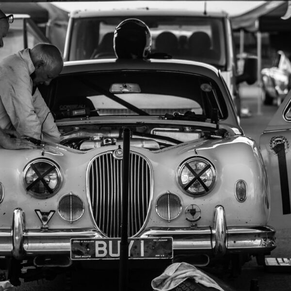 Black and white picture of two men working on vintage jaguar car engine