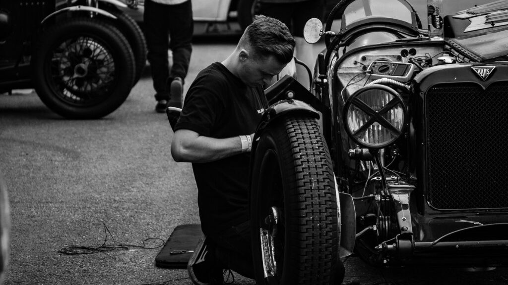Black and white picture of man working on a vintage car