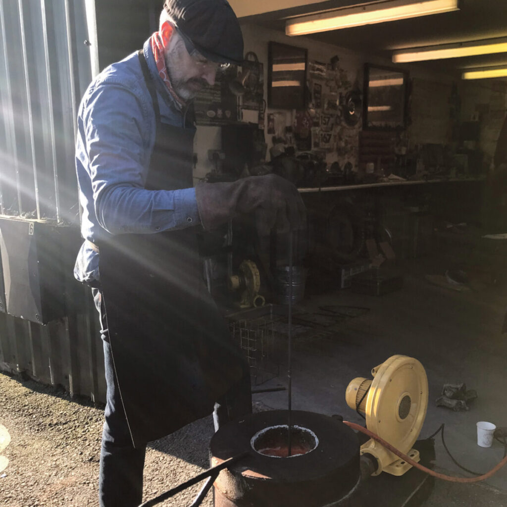 Man standing outside workshop stirring furnace