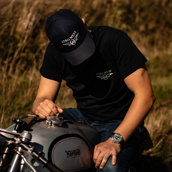 Man wearing zero west cap and t-shirt and watch sitting on motorbike