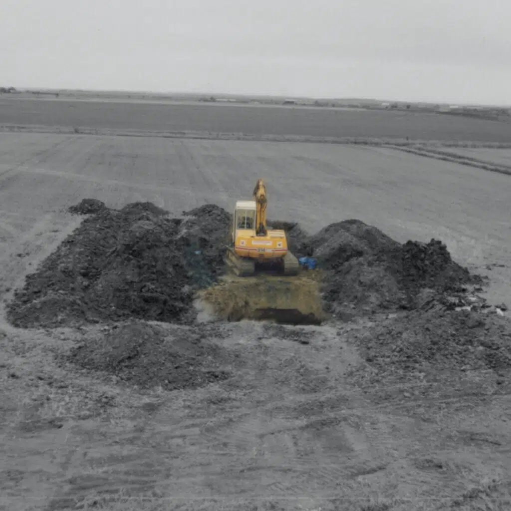 Digger next to hole in the ground in a field