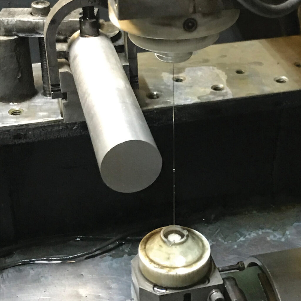 metal bar being wire cut into discs