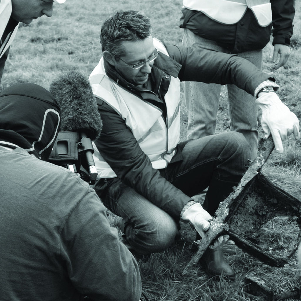 Man holding a piece of metal from Lancaster ED825 which has just been dug up