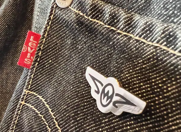 Zero West pin badge on denim grey jacket pocket