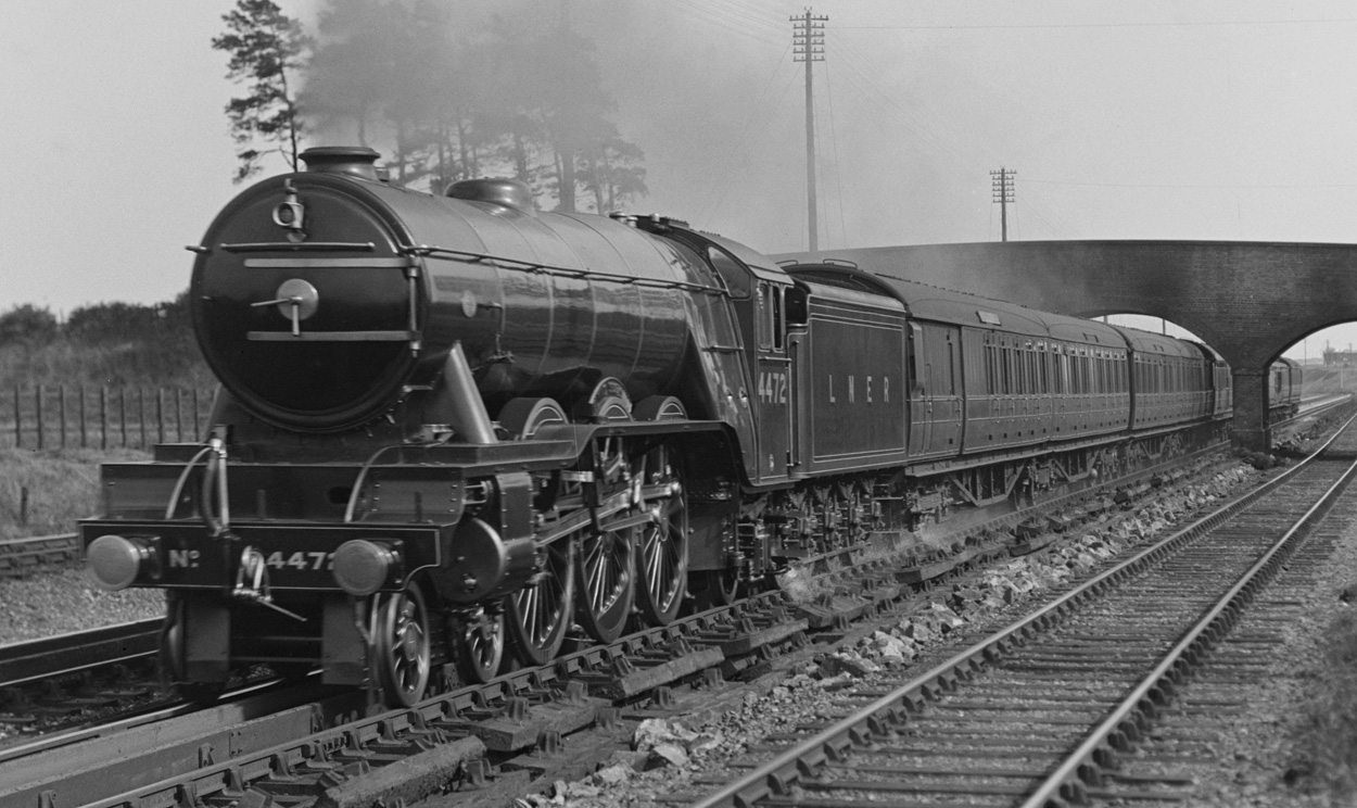 Black and white picture of flying scotsman travelling under a bridge