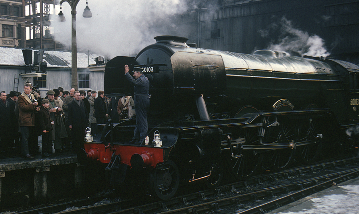 Flying scotsman leaving yard with people watching from platform