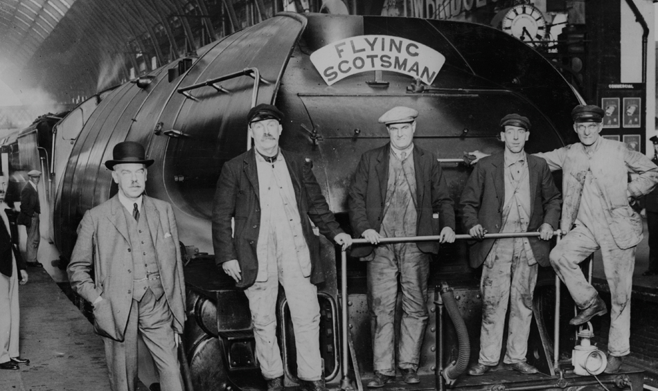 Black and white photo of men standing in front of Flying Scotsman